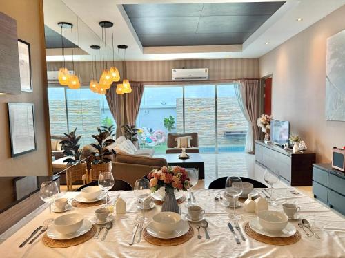 a dining room with a table and a living room at Phirom2 pool villa pattaya in Jomtien Beach