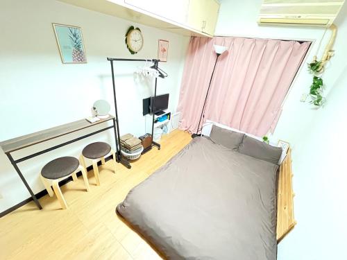 Zimmer mit einem Bett und zwei Stühlen in der Unterkunft Guest House Yakuin INN in Fukuoka