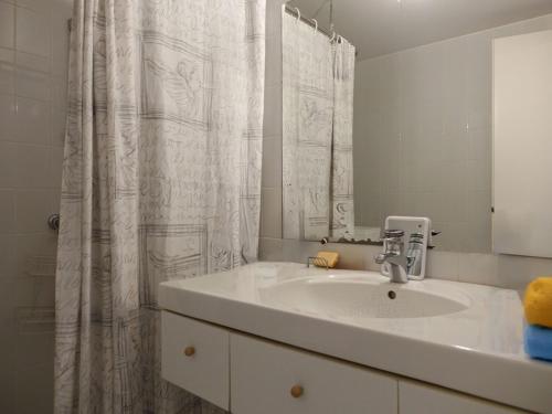 Un baño con lavabo y cortina de ducha. en Maison spacieuse à 400m de la plage des Govelins, vue mer - FR-1-639-138, en Saint-Gildas-de-Rhuys