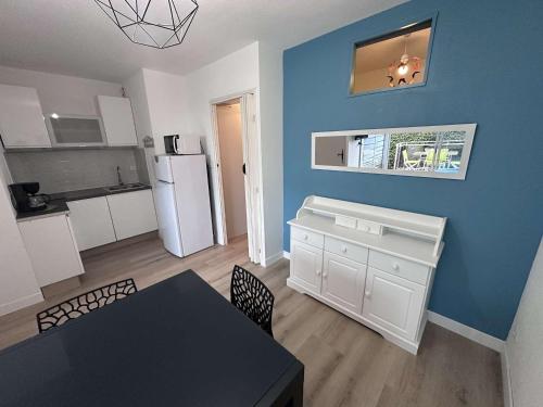 une cuisine avec une table et un mur bleu dans l'établissement Appartement 2 Pièces Climatisé avec Garage - Grau-du-Roi - FR-1-731-131, au Grau-du-Roi