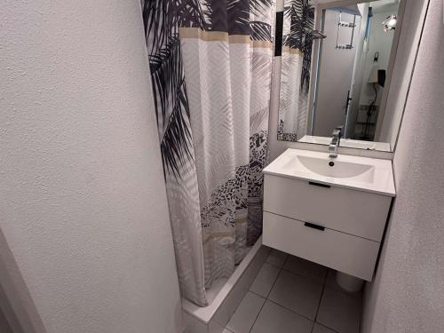 une salle de bain avec un lavabo et un rideau de douche dans l'établissement Appartement 2 Pièces Climatisé avec Garage - Grau-du-Roi - FR-1-731-131, au Grau-du-Roi