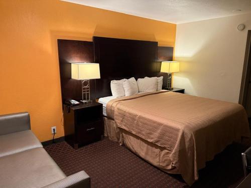 a hotel room with a bed with two lamps and a couch at Hollister Inn in Hollister