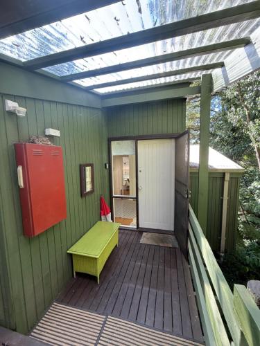 a green house with a green bench on a deck at Sassafras Treehouse Private home in the Dandenong Ranges, Victoria in Sassafras