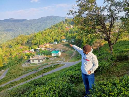 a man standing on a hill looking at a road at Samabeong Homestay Tindhurey in Lava