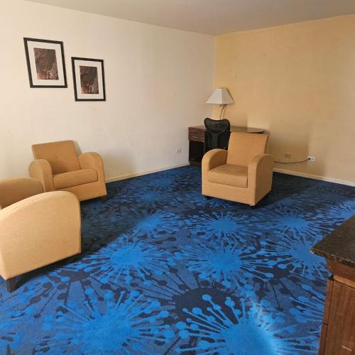a hotel room with two chairs and a blue carpet at Super 8 by Wyndham Denver Central in Denver