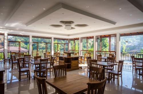 a dining room with tables and chairs and windows at Okwin Resort in Kandy