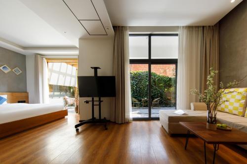 a living room with a bed and a couch and a tv at 慢境Slow Land半山海景花园酒店 in Dali