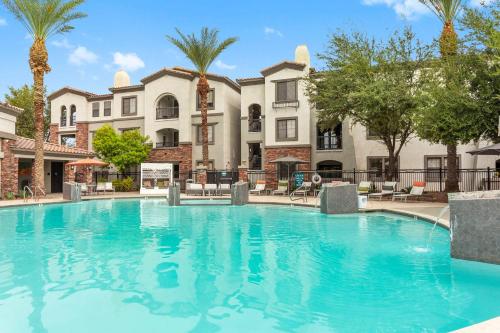 a large swimming pool with palm trees and buildings at CozySuites Glendale by the stadium with pool 31 in Glendale