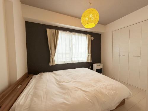 a bedroom with a white bed and a window at Sun Court Nango-dori サンコート南郷通 801 in Sapporo