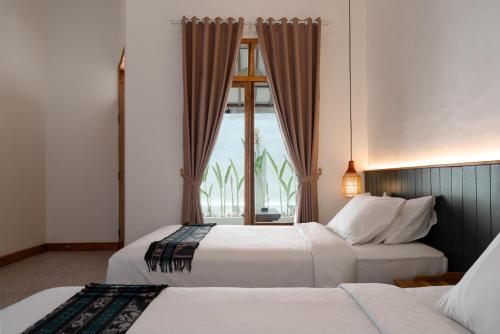 two beds in a hotel room with a window at Green Hill Boutique Hotel in Labuan Bajo