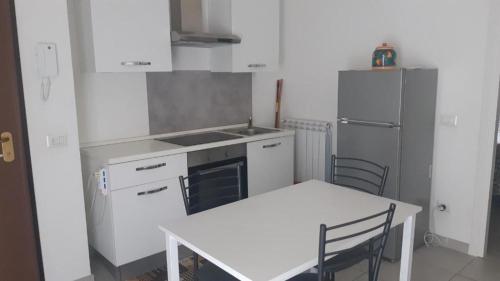 a white kitchen with a table and a refrigerator at ATOS - Camera con Bagno e Cucina privati in Randazzo