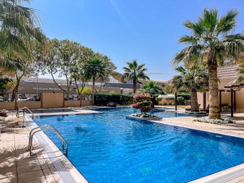 a swimming pool with palm trees in a resort at Modern Renovated Studio Building 197 - 5 Min Walking from Metro and Pavilions in Dubai