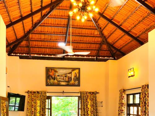 a living room with a ceiling fan and windows at Lar Amorosa Boutique Hotel - Goa in Calangute