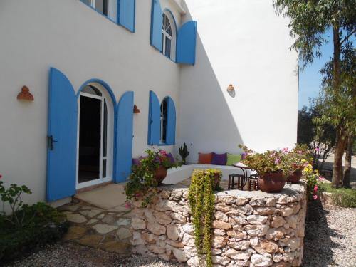 a house with blue and white walls and a stone wall at Villa Daba in Ghazoua