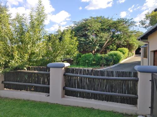 a fence in front of a yard with trees at Sunrise Mountains View in Krugersdorp