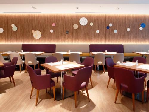 a dining room with tables and chairs and clocks on the wall at Miyako Hotel Kyoto Hachijo in Kyoto