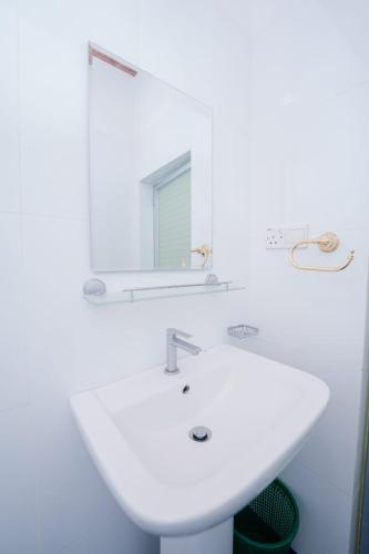 a white bathroom with a sink and a mirror at Suwani Pinnawala Homestay in Pinnawala