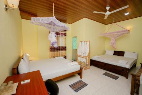 a bedroom with two beds and a table and a ceiling at Suwani Pinnawala Homestay in Pinnawala