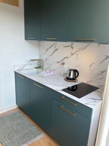 - une cuisine avec des placards bleus et une bouilloire sur le comptoir dans l'établissement Beau studio au cœur de Dinard, à Dinard