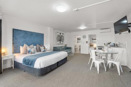a bedroom with a large bed and a table with chairs at Orewa Beachcomber in Orewa