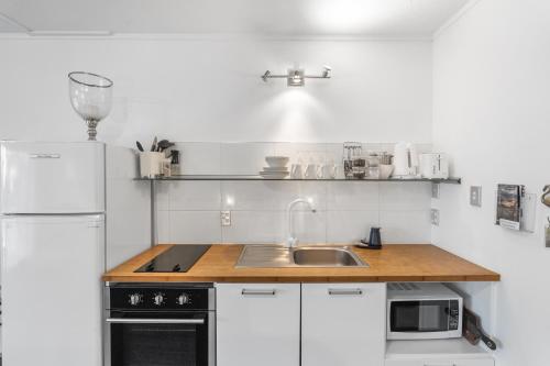 a kitchen with a sink and a white refrigerator at Orewa Beachcomber in Orewa