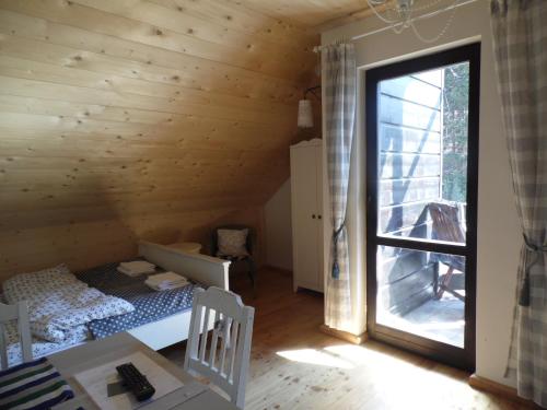 sypialnia z łóżkiem w drewnianym pokoju z oknem w obiekcie Kocia Górka w Wiśle