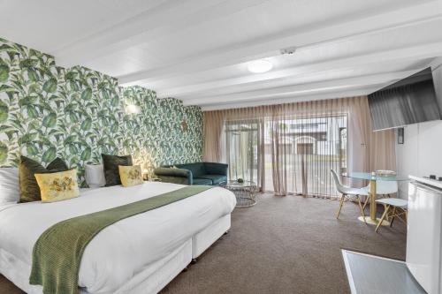 a hotel room with a large bed and a kitchen at Orewa Beachcomber in Orewa