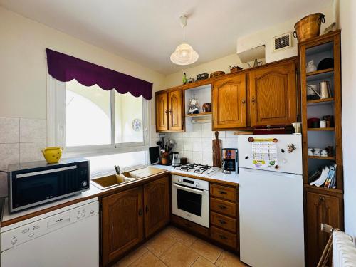 une cuisine avec des armoires en bois et un réfrigérateur blanc dans l'établissement Maison Familiale 8 pers à Fouras, proche plages, 6 chambres - FR-1-709-87, à Fouras