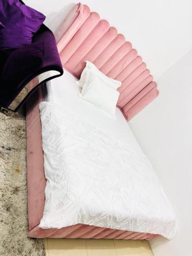 a bed with pink and white sheets and pillows at Ajman holiday home in Ajman 