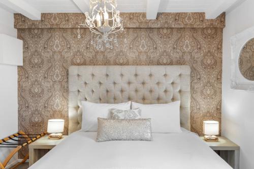 a bedroom with a large white bed with a chandelier at Orewa Beachcomber in Orewa