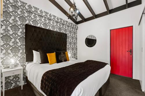 a bedroom with a large bed with a red door at Orewa Beachcomber in Orewa