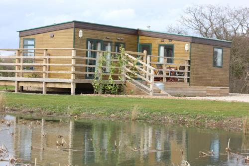 a cabin by a river with ducks in the water at Barker Stakes Farm in Pickering