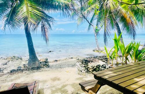 a picnic table on a beach with palm trees at Rangiroa Ohana House in Avatoru