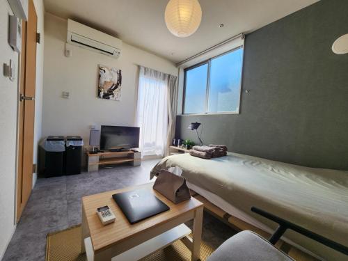 a bedroom with a bed and a table with a laptop on it at The Hotel REPOS SIMOMARUKO in Tokyo