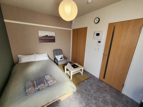 a bedroom with a bed and a chair and a clock at The Hotel REPOS SIMOMARUKO in Tokyo