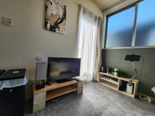 a living room with a large television and a window at The Hotel REPOS SIMOMARUKO in Tokyo