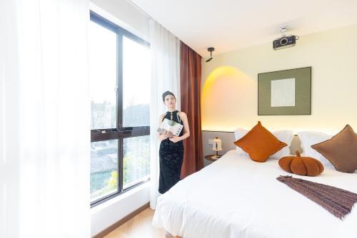 a woman standing in a hotel room with a bed at Wuzhen Xizha Slow Life Riverside Inn in Wujiaqiao
