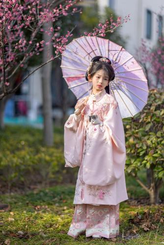 a little girl in a dress holding an umbrella at Wuzhen Xizha Slow Life Riverside Inn in Wujiaqiao