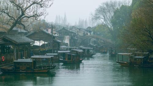 a group of boats on a river in a city at Wuzhen Xizha Slow Life Riverside Inn in Wujiaqiao