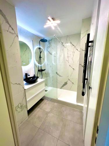 une salle de bain avec une douche avec une porte vitrée dans l'établissement Marseille Superbe T2 Confort & Élégance Parking Privé & Piscine, à Marseille