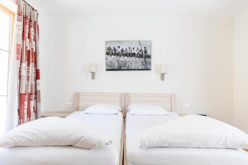 two beds in a white room with a picture on the wall at A Casa Residenz in Sölden