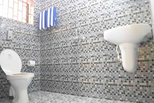 a bathroom with a toilet and a tile wall at C Pearl in Majorda