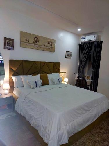 a bedroom with a large white bed and a television at 3Bed Profssnal & Family Friendly with Swimming pool, Work Stns, PS5, Gym & near Beaches in Lagos