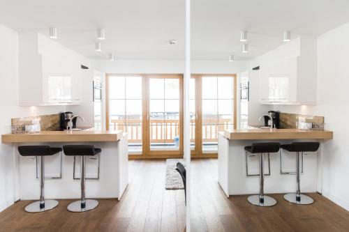 a kitchen with white cabinets and bar stools at A Casa Residenz in Sölden