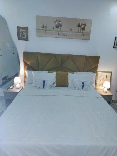 a bedroom with a large white bed with two lamps at 3Bed Profssnal & Family Friendly with Swimming pool, Work Stns, PS5, Gym & near Beaches in Lagos