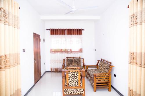 two chairs and a table in a room with curtains at Gin Green Villa in Galle