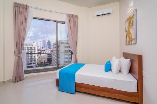a bedroom with a bed and a large window at Marine Suites in Colombo