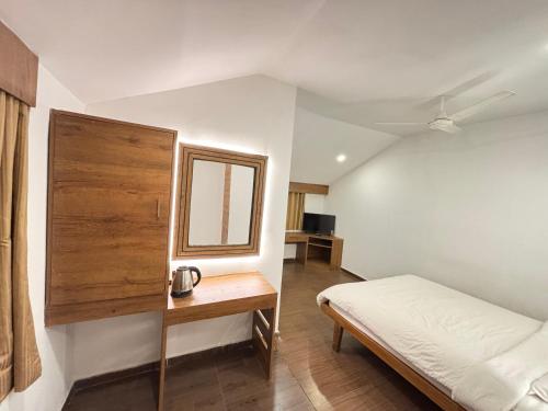 a bedroom with a bed and a table and a mirror at Zeenath Taj Gardens in Yelagiri