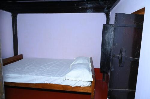 a small bedroom with a bed and a refrigerator at Siri Heritage Homestay in Jadkal