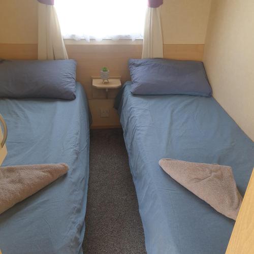 two beds in a small room with a window at Rhyl, Wales, CHESTNUT GARDENS Cost road Rhyl in Meliden